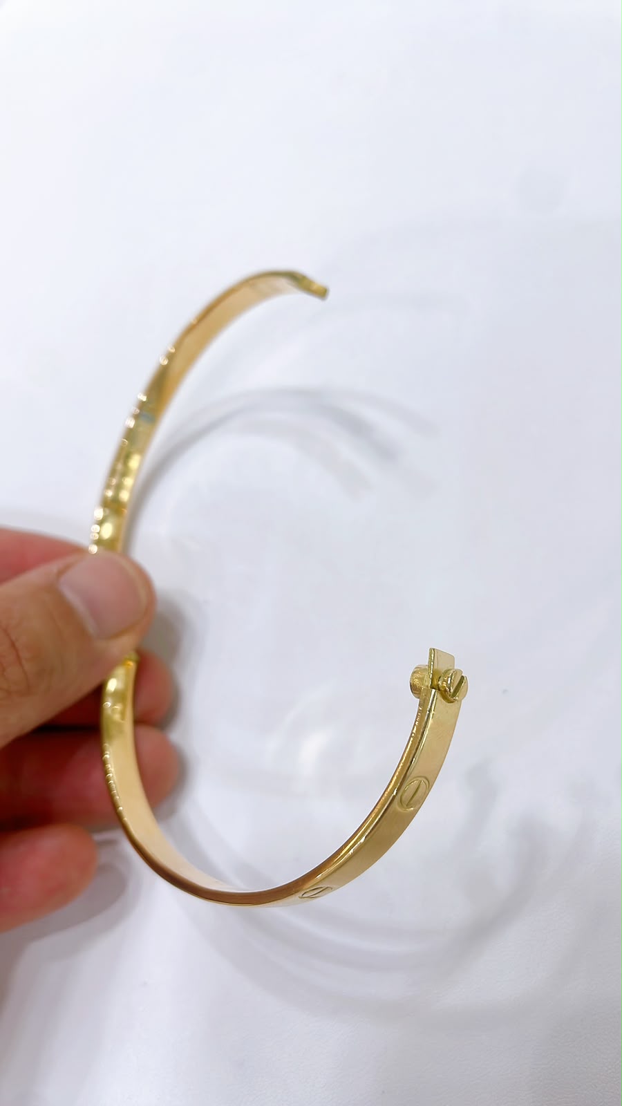 18K Gold Screw Bangle Bracelet held in hand, showcasing its sleek design and luxurious gold finish.