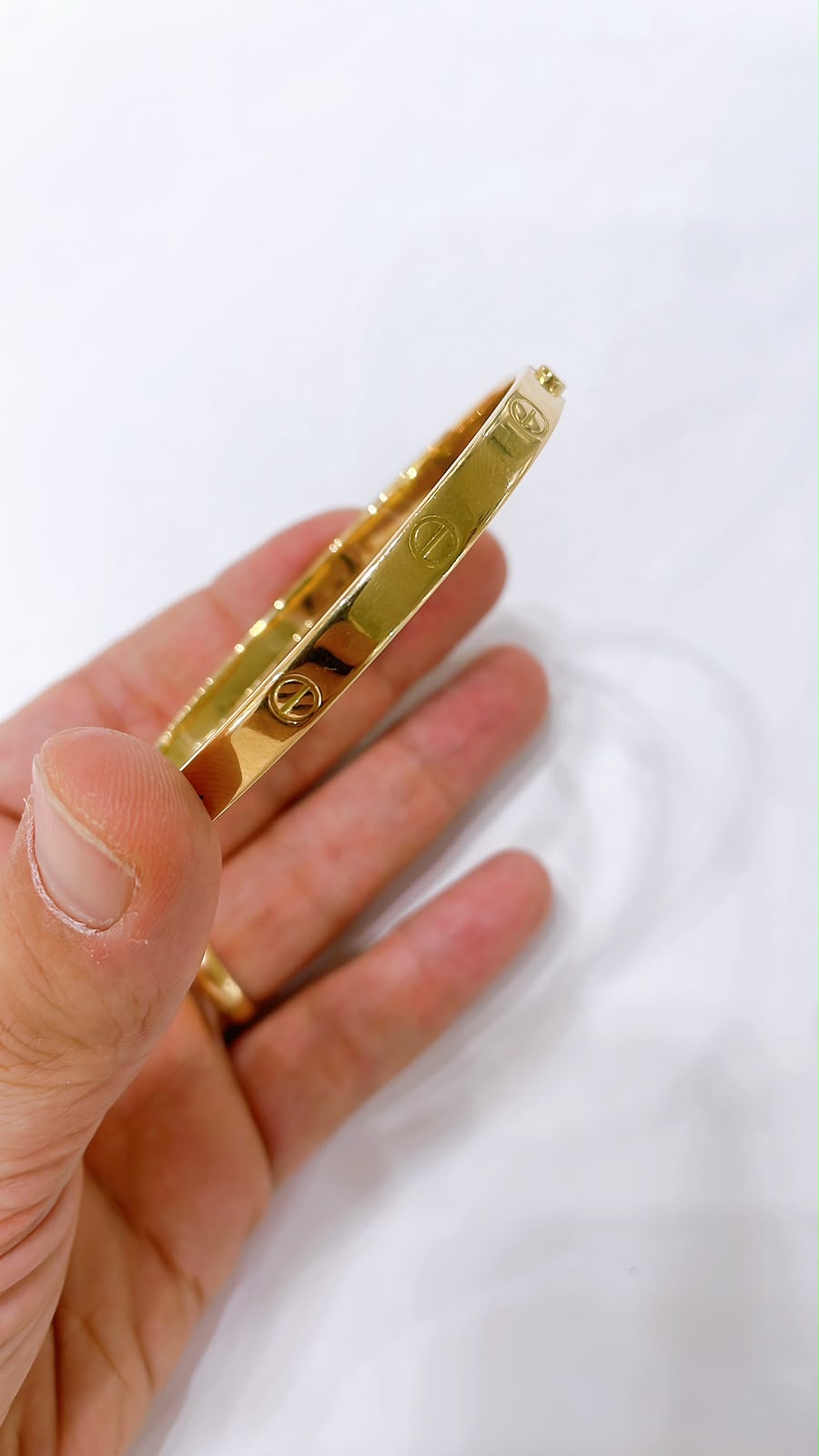 18K Gold Screw Bangle Bracelet held in hand, showcasing its sleek design and polished finish.