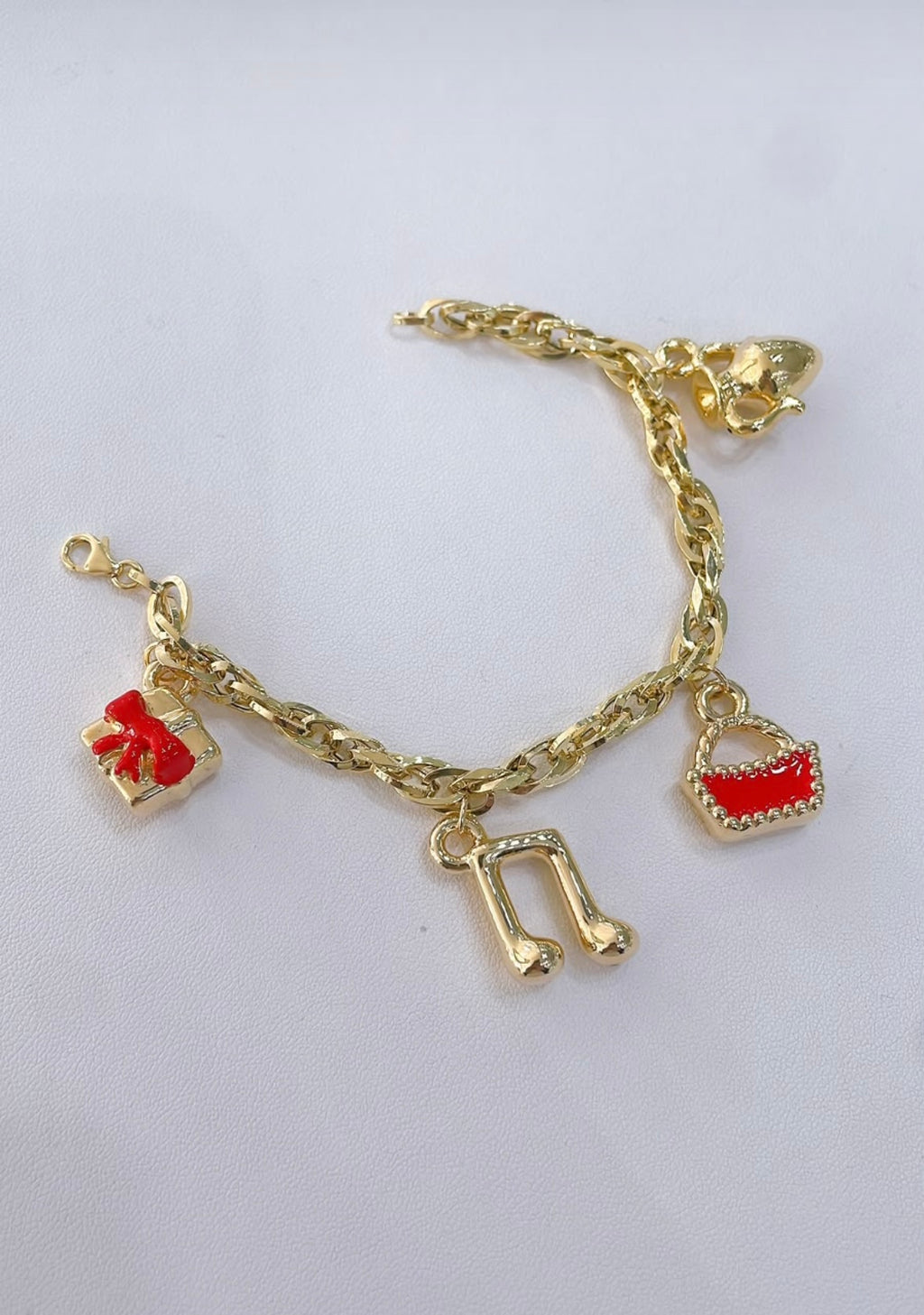 Bracciale a catena con quattro ciondoli in oro giallo 18 kt su sfondo chiaro