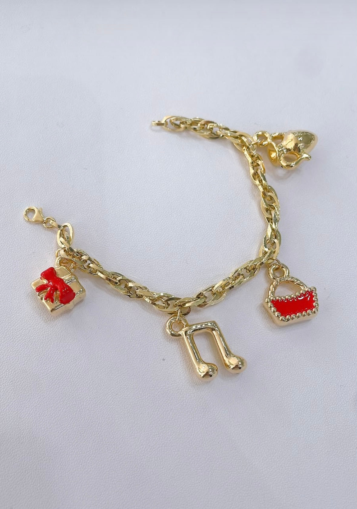 Bracciale a catena con quattro ciondoli in oro giallo 18 kt su sfondo chiaro